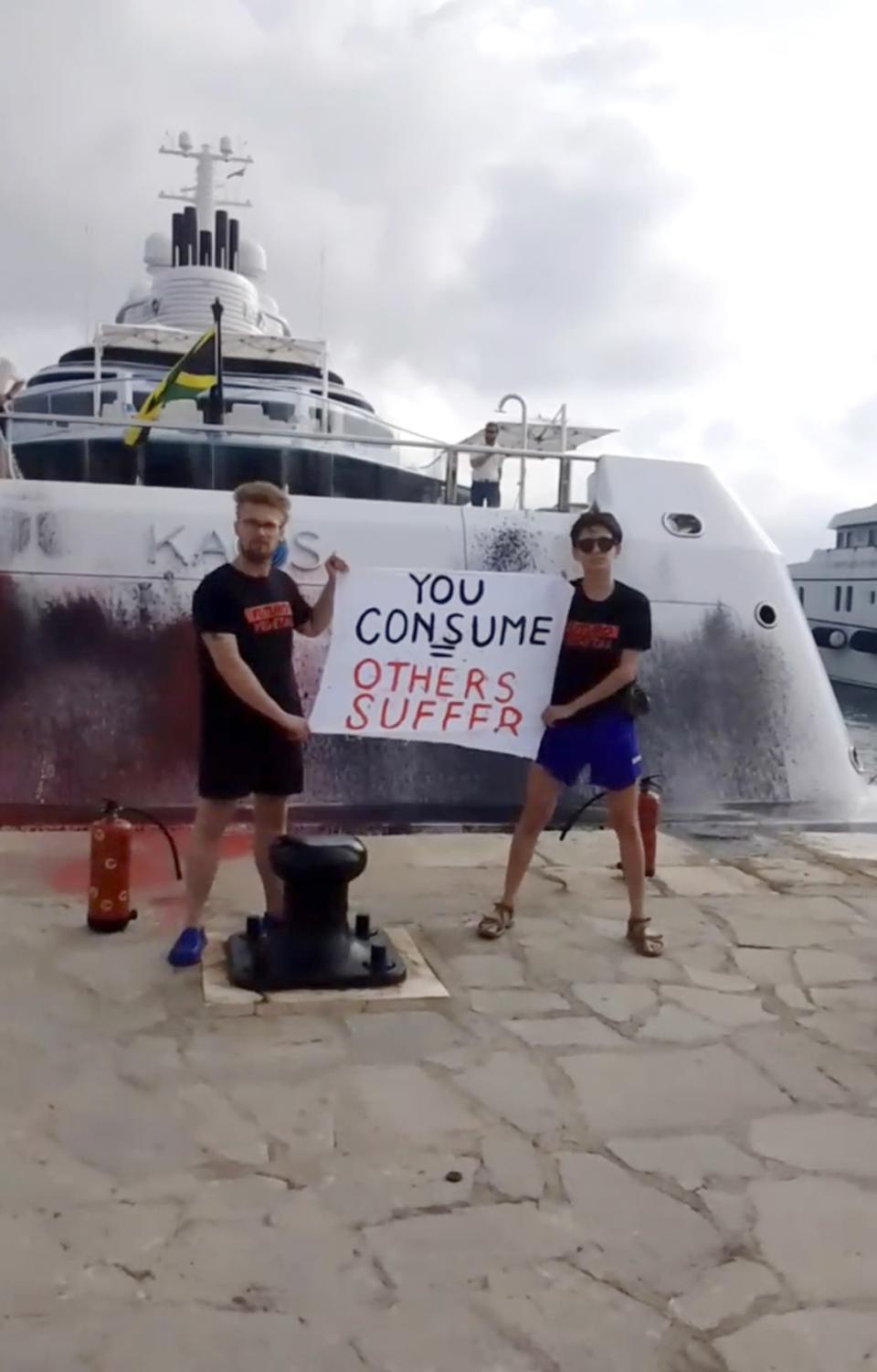 In this frame from video provided by Karen Killeen, protesters demonstrate in front of a super yacht belonging to Walmart heir Nancy Walton Laurie after spray paining it in Ibiza, Spain on July 16, 2023. Climate activists have spraypainted a superyacht, blocked private jets from taking off and plugged holes in golf courses this summer as part of an intensifying campaign against the emissions-spewing lifestyles of the ultrawealthy. (Karen Killeen via AP)