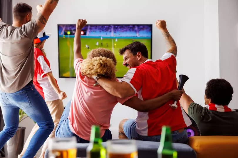 A group of people watching football on a TV