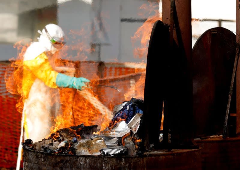 FILE PHOTO: A health worker burns food waste of Ebola patients at incineration part of an Ebola treatment center (ETC) in Katwa