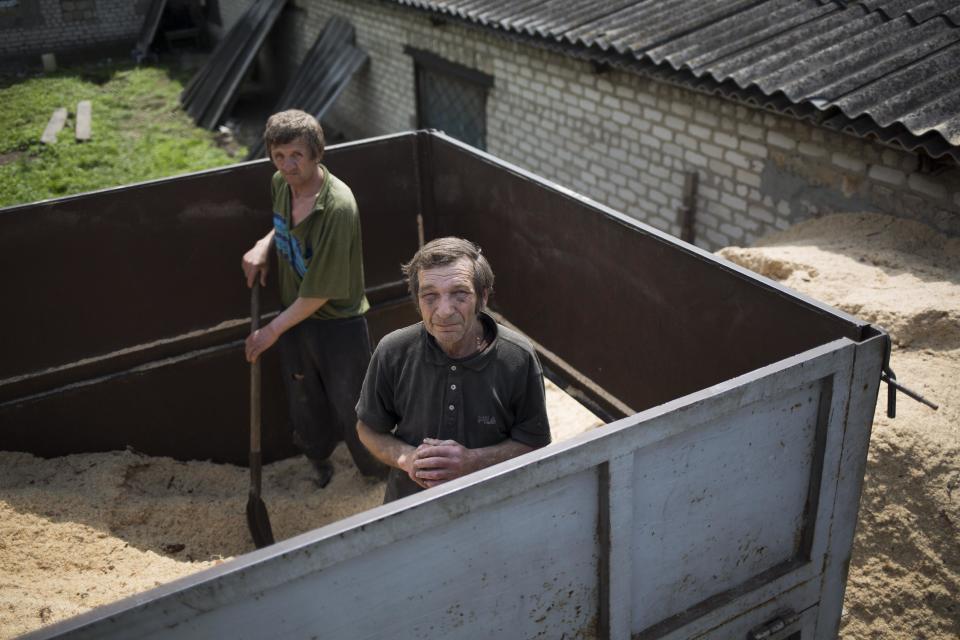 Villagers take a break from shoveling sawdust off a truck at a farm near Korsun, a small town about 30 km north-east from Donetsk, eastern Ukraine, Tuesday, May 13, 2014. People in eastern Ukraine are trying to continue life as usual while their region is gripped by unrest amid an attempt by pro-Russian insurgents to break away their area from the rest of the country. (AP Photo/Alexander Zemlianichenko)