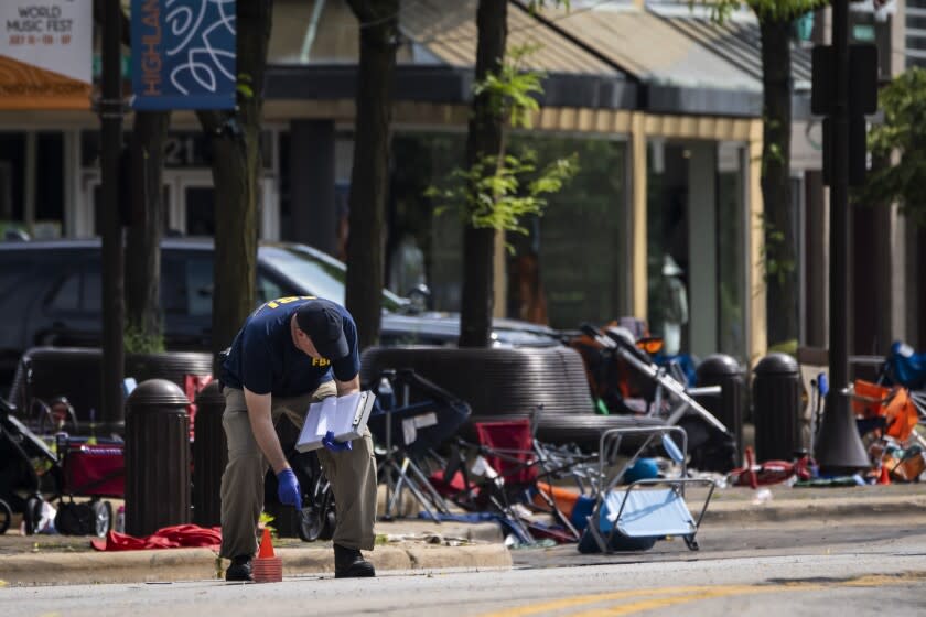 Members of the FBI's Evidence Response Team Unit investigate in downtown Highland Park, Ill., the day after a deadly mass shooting on Tuesday, July 5, 2022. Police say the gunman who attacked an Independence Day parade in suburban Chicago fired more than 70 rounds with an AR-15-style gun. (Ashlee Rezin /Chicago Sun-Times via AP)