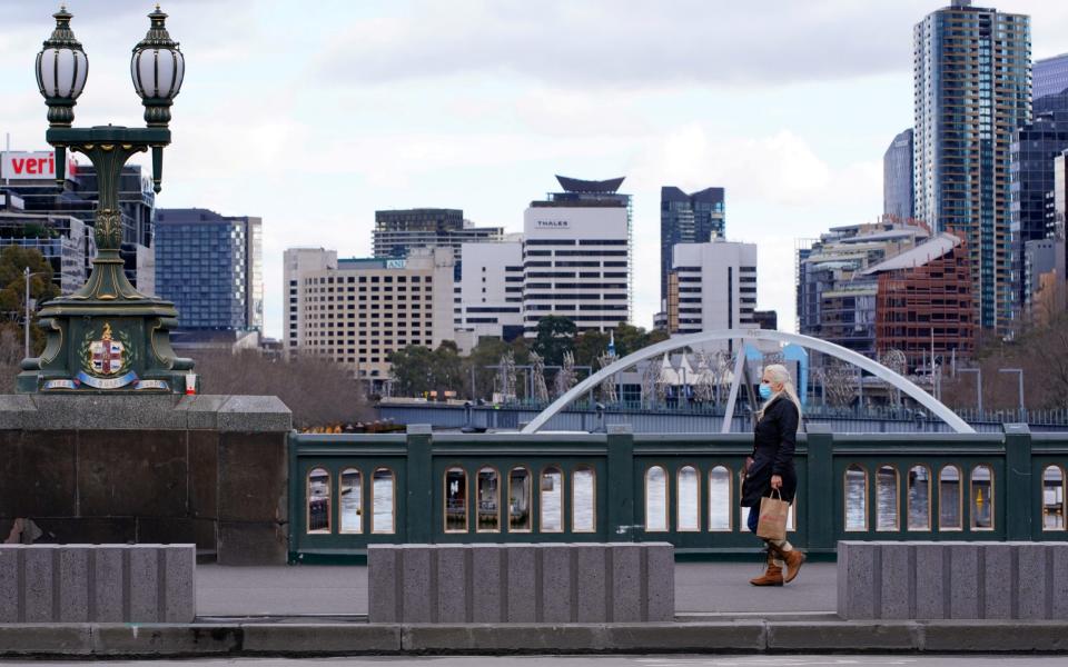 A lone woman, wearing a protective face mask, walks across an unusually quiet city centre bridge on the first day of a lockdown as the state of Victoria looks to curb the spread of a coronavirus disease (COVID-19) outbreak in Melbourne, Australia, July 16, 2021.  - Reuters