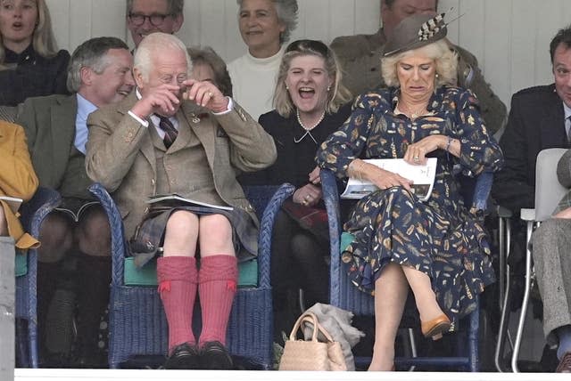 Charles, wiping his eyes with laughter, and Camilla watching the Highland Games at the Braemar Gathering