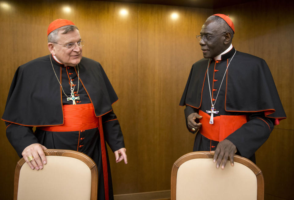 FILE - Cardinal Raymond Leo Burke, left, talks with Cardinal Robert Sarah, prefect of the Congregation for Divine Worship and the Discipline of the Sacraments, as he arrives for the presentation of his book Divine Love Made Flesh, in Rome, Wednesday, Oct. 14, 2015. Five conservative cardinals are challenging Pope Francis to affirm Catholic teaching on homosexuality and female ordination. They've asked him to respond ahead of a big Vatican meeting where such hot-button issues are up for debate.The cardinals on Monday published five questions they submitted to Francis, known as “dubia.” (AP Photo/Andrew Medichini, File)
