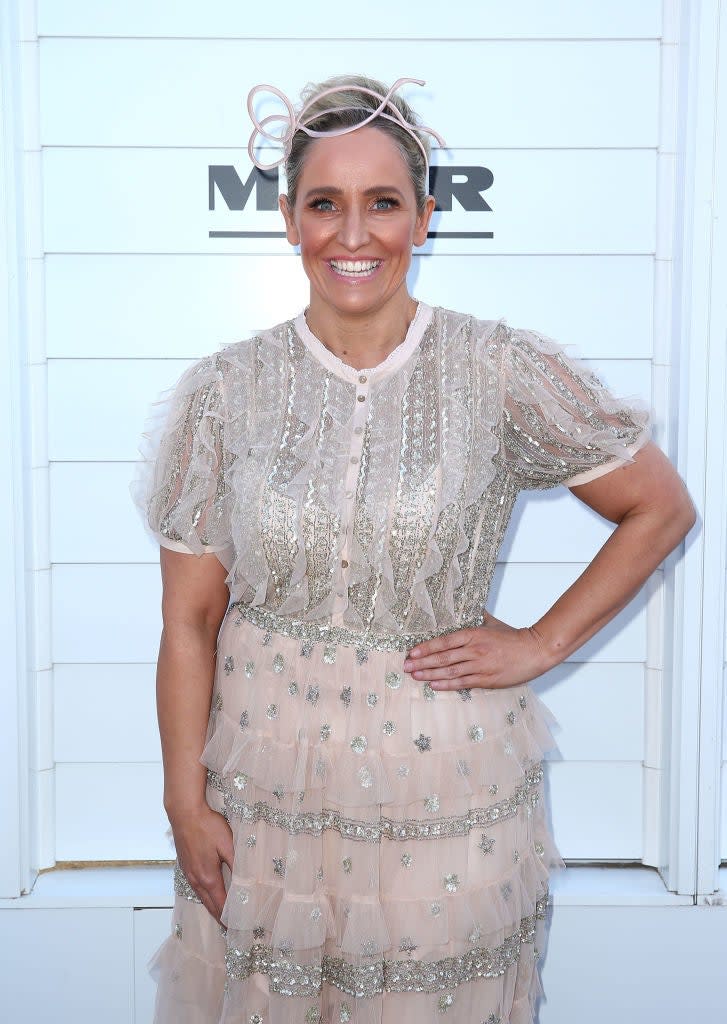 Fifi Box wearing a ruffled, sheer dress with metallic embellishments and a headpiece, smiles at an event