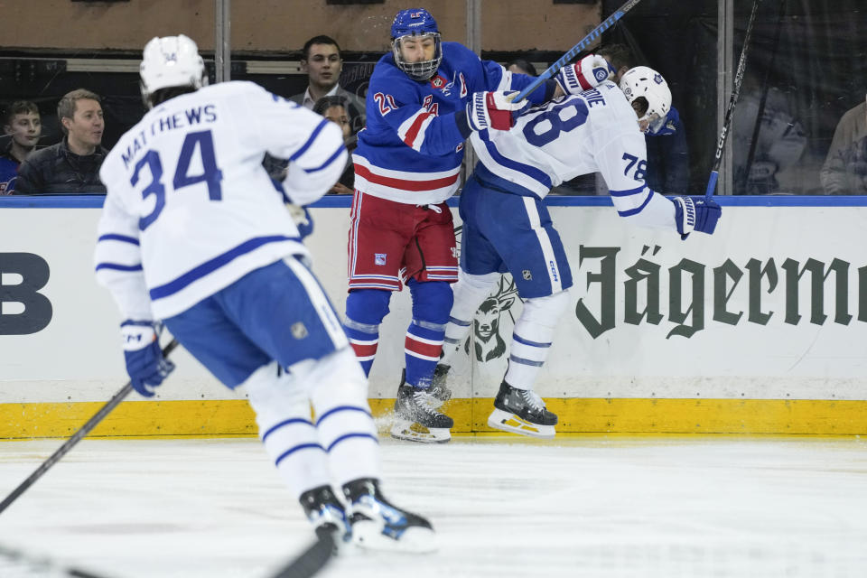 New York Rangers' Barclay Goodrow, center, hits Toronto Maple Leafs' TJ Brodie, right, during the first period of an NHL hockey game, Tuesday, Dec. 12, 2023, in New York. (AP Photo/Seth Wenig)