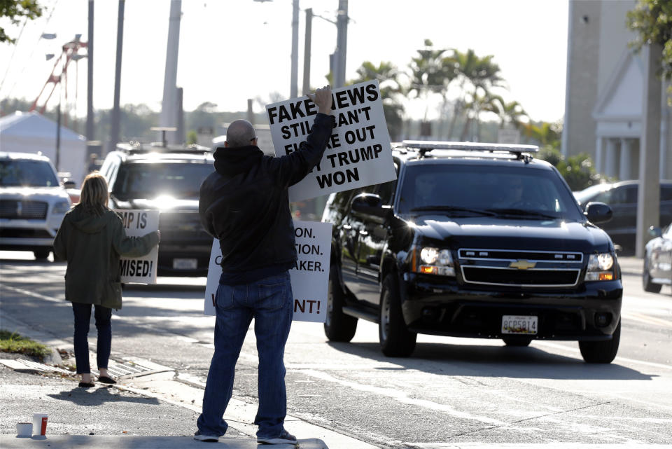 People hold signs as the motorcade of President Donald Trump passes on Saturday, March 23, 2019, in West Palm Beach, Fla. Special counsel Robert Mueller closed his long and contentious Russia investigation with no new charges, ending the probe that has cast a dark shadow over Trump's presidency. (AP Photo/Terry Renna)