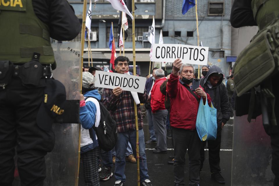 FILE - Supporters of Peruvian President Pedro Castillo hold signs with the Spanish words for, "Sell outs," left, and "Corrupt," as they call for the dissolution of Congress, where lawmakers have sought to remove him twice, as Castillo gives his annual address at Congress on Independence Day in Lima, Peru, July 28, 2022. (AP Photo/Guadalupe Pardo, File)