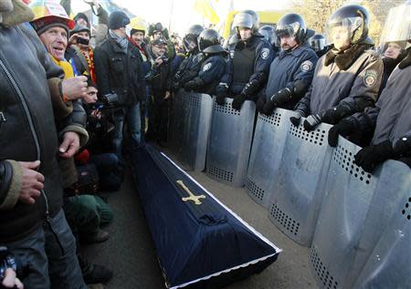 Interior Ministry members stand guard as pro-European integration supporters hold a rally, with a coffin seen in the middle, near the residence of Ukraine's President Viktor Yanukovich located outside Kiev, December 29, 2013. REUTERS/Gleb Garanich