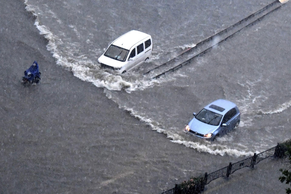 In this photo released by Xinhua News Agency, vehicles pass through floodwaters in Zhengzhou in central China's Henan Province on Tuesday, July 20, 2021. At least a dozen people died in severe flooding Tuesday in a Chinese provincial capital that trapped people in subways and schools, washed away vehicles and stranded people in their workplaces overnight. (Zhu Xiang/Xinhua via AP)