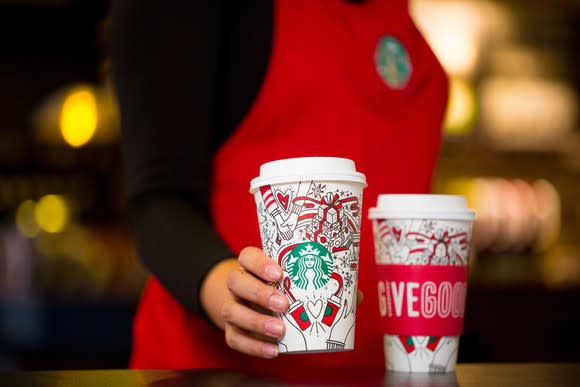 A Starbucks barista passing a coffee cup to a customer