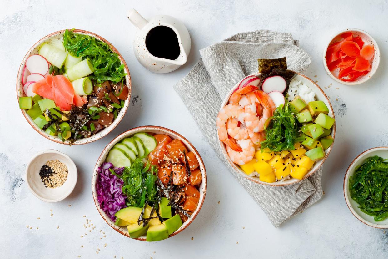 Hawaiian salmon, tuna and shrimp poke bowls with seaweed, avocado, mango, pickled ginger, sesame seeds. Top view, overhead, flat lay