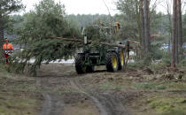 In this Wednesday, Jan. 8, 2020 photo a tractor lifts a tree at the site of the planned new Tesla Gigafactory in Gruenheide near Berlin, Germany. Tesla CEO Elon Musk said during an awards ceremony in Berlin in November 2019 that 'we have decided to put the Tesla Gigafactory Europe in the Berlin area.' The company will also set up an engineering and design center in Berlin, Musk said. He wrote on Twitter that the new plant 'will build batteries, powertrains & vehicles, starting with Model Y.' (AP Photo/Michael Sohn)