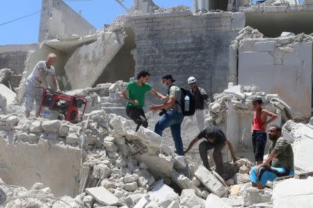 People walk on the rubble of a site hit by a barrel bomb in the rebel held area of Old Aleppo, Syria July 11, 2016. REUTERS/Abdalrhman Ismail