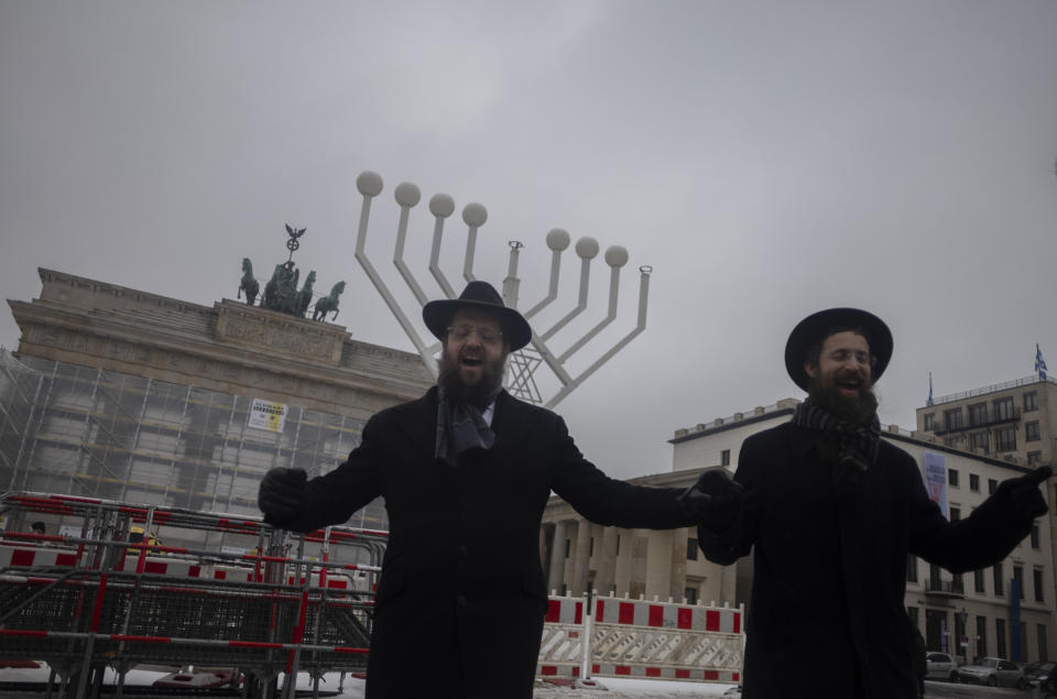 FILE - Rabbi Yehuda Teichtal, right, and Rabbi Shmuel Segal dance in front of a giant Hanukkah Menorah, after it was set up by the Jewish Chabad Educational Center ahead of the Jewish Hanukkah holiday, in front of the Brandenburg Gate at the Pariser Platz in central Berlin, Germany, Wednesday, Dec. 6, 2023. Holocaust survivors from around the globe will mark the start of the fifth day of Hanukkah together with a virtual ceremony as worries grow among Jews worldwide about the Israel-Hamas war and a spike of antisemitism in Europe, the United States and elsewhere. (AP Photo/Markus Schreiber, File)