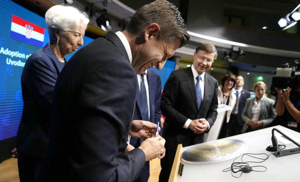 Croatia's Finance Minister Zdravko Maric, second left, signs a cardboard euro coin after a signing ceremony for Croatia to join the euro in Brussels, Tuesday, July 12, 2022. The European Union is set on Tuesday to remove the final obstacles for Croatia to adopt the euro, ensuring the first expansion of the currency bloc in almost a decade. (AP Photo/Virginia Mayo)