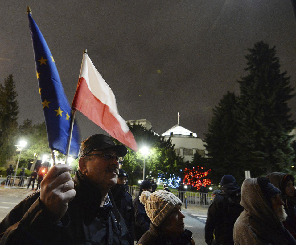A man holding a Poland and European Union flags take part in a protest outside Poland's parliament building as lawmakers voted to approve the much-criticized legislation that allows politicians to fire judges who criticize their decisions, in Warsaw, Poland, Thursday, Jan. 23, 2020. Poland's lawmakers gave their final approval Thursday to legislation that will allow politicians to fire judges who criticize their decisions, a change that European legal experts warn will undermine judicial independence. (AP Photo/Czarek Sokolowski)