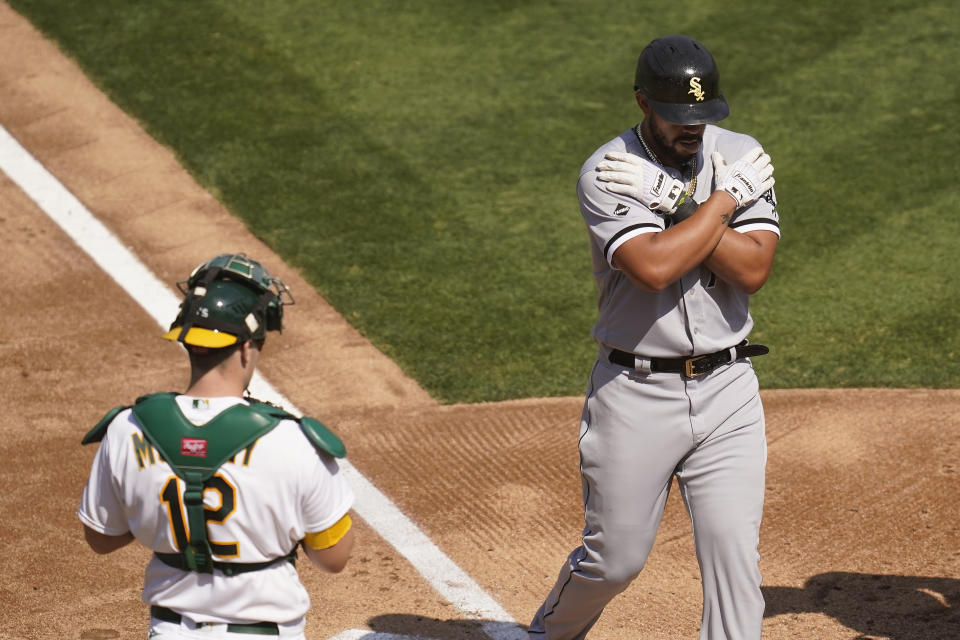 Chicago White Sox's Jose Abreu, right, reacts after hitting a two-run home run as Oakland Athletics catcher Sean Murphy (12) looks on during the third inning in Game 1 of an American League wild-card baseball series Tuesday, Sept. 29, 2020, in Oakland, Calif. (AP Photo/Eric Risberg)