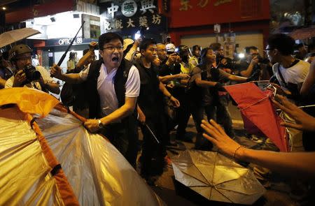 A police officer removes a tent from a protest site during a clash with pro-democracy protesters at the Mongkok shopping district of Hong Kong October 19, 2014. REUTERS/Carlos Barria