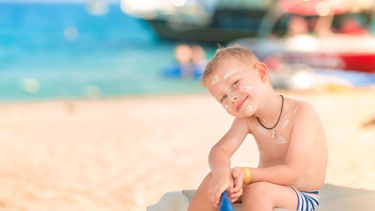 Niño con crema solar en la playa