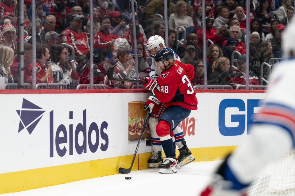 Washington Capitals defenseman Rasmus Sandin (38) and New York Rangers center Nick Bonino (12) battle for control of the puck during the second period of an NHL hockey game, Saturday, Dec. 9, 2023, in Washington. (AP Photo/Stephanie Scarbrough)