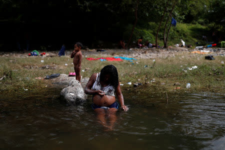 Eight months pregnant Honduran migrant Erly Marcial, 21, takes a bath in the river next to her son David, 2, while they stay with fellow migrants in Tapanatepec, Mexico, November 6, 2018. REUTERS/Carlos Garcia Rawlins