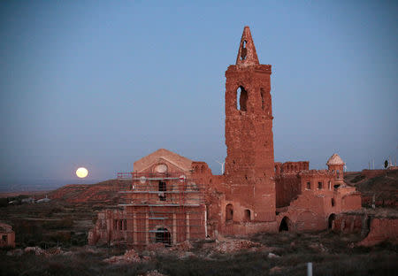 The moon rises behind the San Martin de Tours church in the old village of Belchite, in northern Spain, November 14, 2016. REUTERS/Andrea Comas