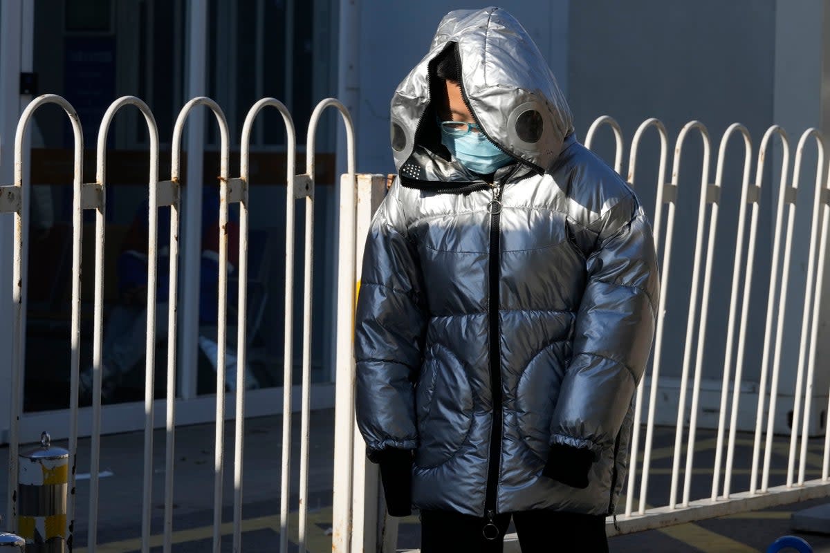 A child wearing a mask passes by a children’s hospital in Beijing (AP)