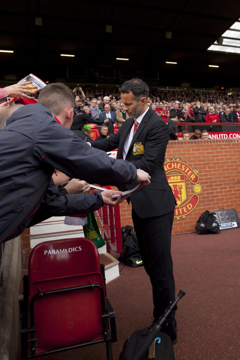 Manchester United's interim manager Ryan Giggs signs autographs as he takes to the touchline before his team's English Premier League soccer match against Norwich City at Old Trafford Stadium, Manchester, England, Saturday April 26, 2014. (AP Photo/Jon Super)