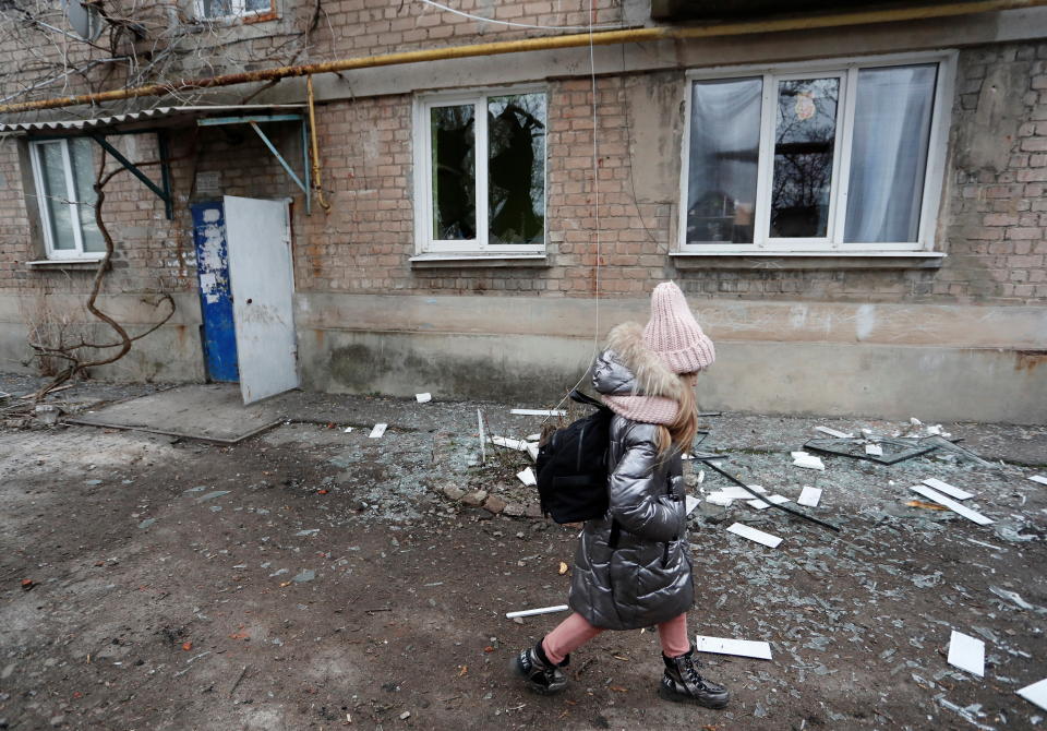 A girl walks past an apartment building, which locals said was damaged by recent shelling, in the separatist-controlled town of Yasynuvata (Yasinovataya) in the Donetsk region, Ukraine February 24, 2022. REUTERS/Alexander Ermochenko