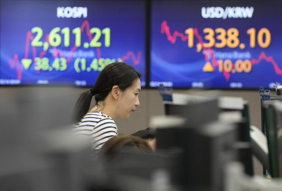 A currency trader watches monitors near the screens showing the Korea Composite Stock Price Index (KOSPI), left, and the foreign exchange rate between U.S. dollar and South Korean won at the foreign exchange dealing room of the KEB Hana Bank headquarters in Seoul, South Korea, Wednesday, Feb. 14, 2024. Asian shares declined Wednesday, after disappointing U.S. inflation data sent shares sliding on Wall Street, raising prospects that interest rates will stay high for longer. (AP Photo/Ahn Young-joon)