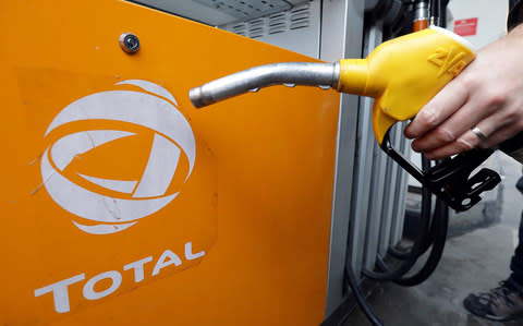 A customer holds a gas pump as he fills-up his car in a Total station in Nice, France - Credit: Eric Gaillard/Reuters