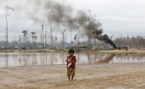 FILE PHOTO: A boy carries a dog as he stands after a Peruvian police operation to destroy illegal gold mining camps in a zone known as Mega 14, in the southern Amazon region of Madre de Dios, Peru, July 14, 2015. REUTERS/Janine Costa/File Photo