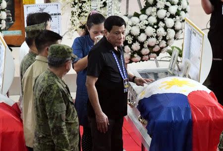 Philippine President Rodrigo Duterte stands with Gricel, wife of Army Corporal Nino Christopher Talabor, who according to authorities was killed by members of rebel group New People's Army (NPA) on Wednesday, the same day the group announced that it is terminating the unilateral ceasefire, during Talabor's wake at Camp Evangelista, Cagayan de Oro city, southern Philippines February 5, 2017. REUTERS/Froilan Gallardo