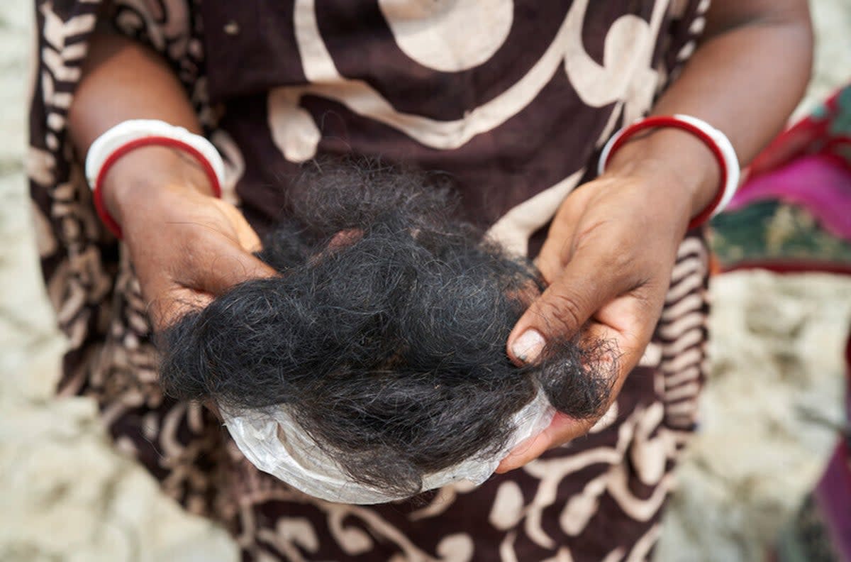 Shyamoli, 50, a local doula, holding hair she believes she has lost as a result of bathing in pondwater contaminated by salt water and farming pesticides (WaterAid/Fabeha Monir)