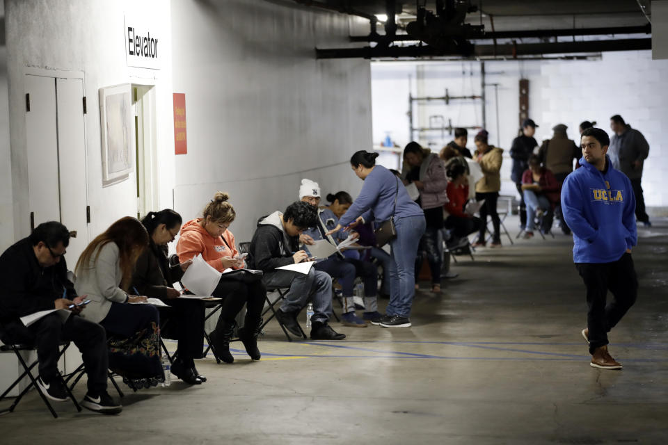 FILE - In this March 13, 2020 file photo, unionized hospitality workers wait in line in a basement garage to apply for unemployment benefits at the Hospitality Training Academy in Los Angeles.  More than 6.6 million Americans applied for unemployment benefits last week, far exceeding a record high set just last week, a sign that layoffs are accelerating in the midst of the coronavirus.   (AP Photo/Marcio Jose Sanchez, File)