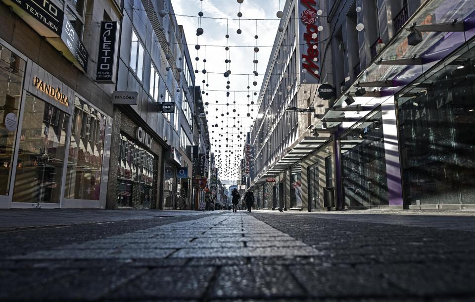 FILE - In this Dec. 16, 2020 file photo, people walk in a shopping road during the lockdown in Cologne Germany. Germany’s leading economic institutes has downgraded their forecast for Europe’s biggest economy saying it is still shaped by the impact of the coronavirus pandemic and that global supply bottlenecks also hamper the country’s recovery. (AP Photo/Martin Meissner, File)