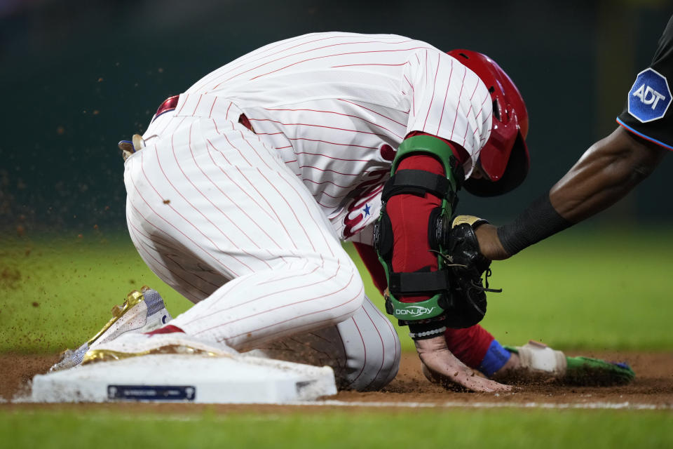 Philadelphia Phillies' Bryce Harper, left, beats the tag from Miami Marlins first baseman Josh Bell on a pickoff attempt during the sixth inning of Game 2 in an NL wild-card baseball playoff series, Wednesday, Oct. 4, 2023, in Philadelphia. (AP Photo/Matt Slocum)