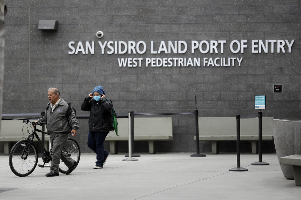 FILE - In this March 20, 2020 file photo a woman adjusts her hat and mask as she arrives from Tijuana, Mexico, crossing by foot at the San Ysidro port of entry in San Diego. An increasing number of American citizens have been apprehended as they have tried to smuggle illegal drugs into the U.S. since the start of the coronavirus pandemic, an uptick that's come amid travel restrictions at the border with Mexico. (AP Photo/Gregory Bull, File)