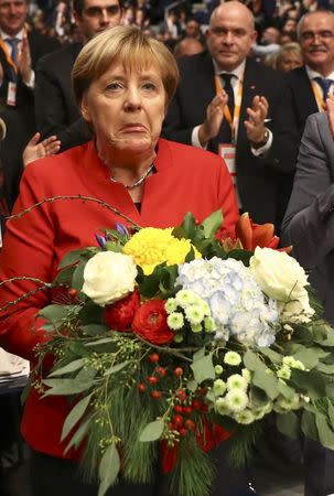 German Chancellor and leader of the conservative Christian Democratic Union party CDU Angela Merkel receives flowers after she was re-elected as chairwoman at the CDU party convention in Essen, Germany, December 6, 2016. REUTERS/Kai Pfaffenbach TPX IMAGES OF THE DAY