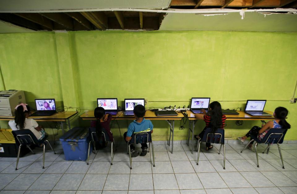 Migrant children watch laptops inside the Agape World Mission shelter used mostly by Mexican and Central American migrants who are applying for asylum in the U.S., on the border in Tijuana, Mexico, Monday, June 10, 2019. (AP Photo/Eduardo Verdugo)