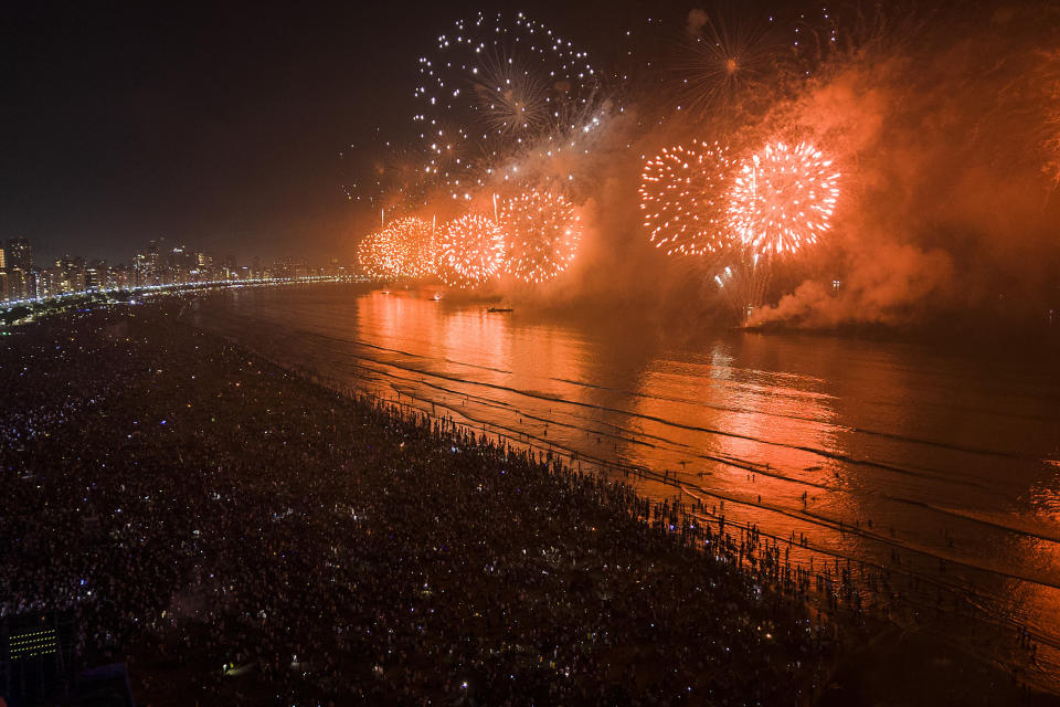 People bring in the New Year as they watch fireworks explode over Santos Bay, in Santos, Brazil, early Sunday, Jan. 1, 2023. (AP Photo/Matias Delacroix)