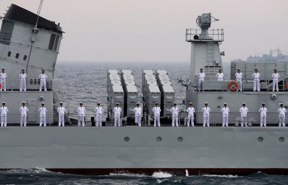 Chinese soliders stand in a line on a warship