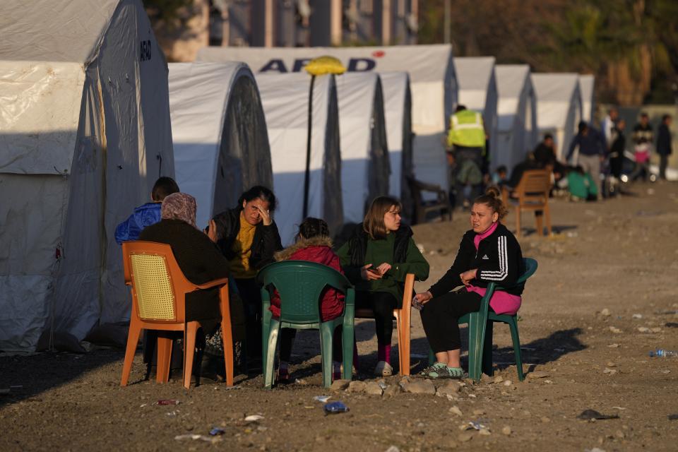 People who lost their houses in the devastating earthquake, sit outside their tent at a makeshift camp, in Iskenderun city, southern Turkey, Tuesday, Feb. 14, 2023. Thousands left homeless by a massive earthquake that struck Turkey and Syria a week ago packed into crowded tents or lined up in the streets for hot meals as the desperate search for survivors entered what was likely its last hours. (AP Photo/Hussein Malla)
