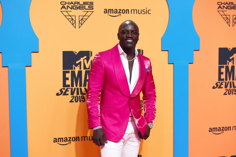 Entertainer Akon wearing a pink blazer posing for a picture.