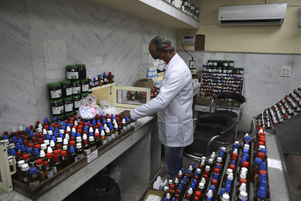 In this Thursday, March 12, 2020, photo, a doctor makes homeopathic pills in New Delhi, India. With no approved drugs for COVID-19, some people are turning to alternative medicines without evidence that they work. (AP Photo/Manish Swarup)