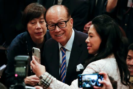 FILE PHOTO: Hong Kong tycoon Li Ka-shing takes a selfie with journalists after announcing his retirement in Hong Kong