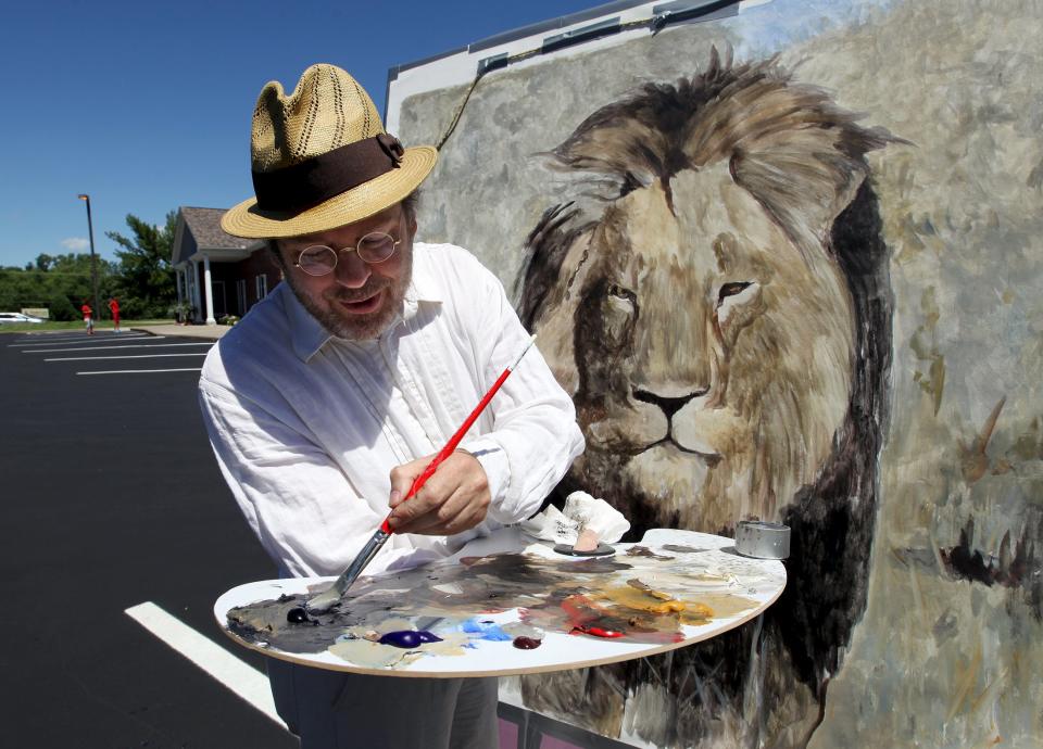 Mark Balma, an international artist based in California and Florence, Italy, paints a lion head on a canvas in the parking lot of River Bluff Dental clinic in protest against the killing of a famous lion in Zimbabwe, in Bloomington, Minnesota July 29, 2015. (REUTERS/Eric Miller)