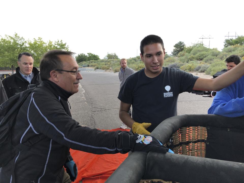 Elijah Sanchez, center, helps passenger board a hot air balloon in Albuquerque, N.M., on Tuesday, Oct. 1, 2019. Sanchez, 20, will be among the youngest pilots to launch as part of this year's Albuquerque International Balloon Fiesta. The nine-day event is expected to draw several hundred thousand spectators and hundreds of balloonists from around the world. It will kick off Oct. 5 with a mass ascension. (AP Photo/Susan Montoya Bryan)