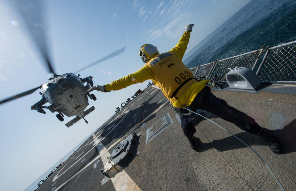  Boatswain’s Mate 2nd Class John Acheson signals an MH-60S Sea Hawk helicopter from the Desert Hawks of Helicopter Sea Combat Squadron (HSC) 26 to land during flight operations aboard the Arleigh Burke-Class guided-missile destroyer USS Mitscher (DDG 57). 